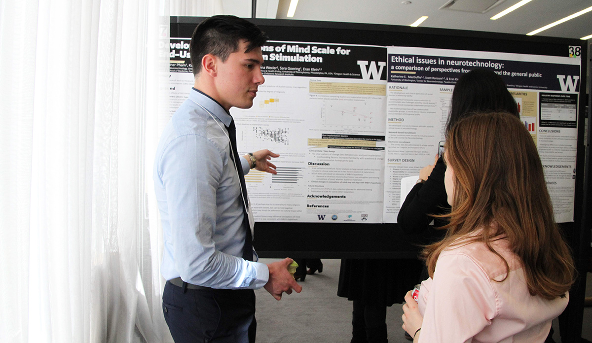 Photo of Christopher Pham pointing at his poster while talking to Deena Kopyto