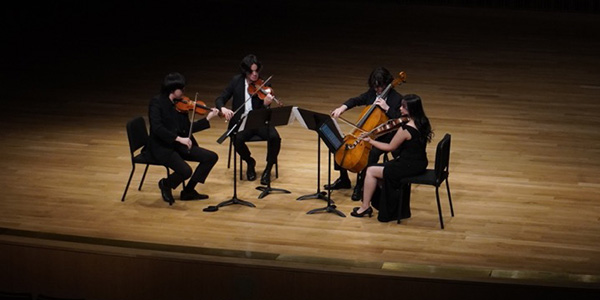 Nosremé Quartet performin on stage in spotlight with black backgroun. Image courtesy of Hsin Ching